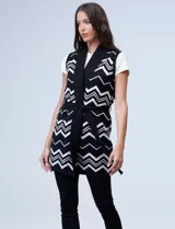 Chaleco largo tejido con cuello solapa, bolsillos delanteros, pasadores en la cintura y lazo para ajustar. Diseño con patrón de zigzag en blanco y negro.