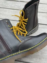 Bota corta de cuero color chocolate, con cordones amarillos y cierre lateral.