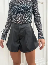 Short negro de cuerina con pinzas delanteras y cierre con botón.