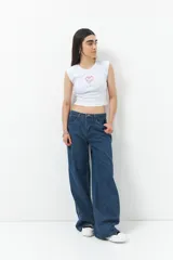 Pantalón de jean ancho color negro, de tiro bajo y confeccionado en algodón. Cuenta con una línea bordada color marrón en ambas piernas y cinco bolsillos.