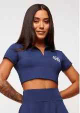 Top cropped azul marino con cuello polo y mangas cortas. Presenta un logo estampado en el pecho.