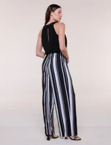 Enterito largo sin mangas con cuerpo negro de escote alto y pantalón wide leg de rayas verticales blancas y negras, con cintura elastizada y cordón ajustable.