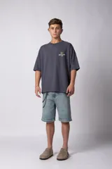 Remera de corte oversize color gris oscuro, confeccionada en algodón premium de alto gramaje. Presenta un diseño minimalista con un pequeño estampado frontal que incluye un oso y el texto 'Richer & Louder VCP'.