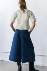 Jeans de tiro medio con diseño culotte y pierna ancha. Presenta cinco bolsillos, detalle de pinzas en el delantero y cierre frontal con cremallera y botón metálico.