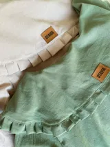 Camisa verde confeccionada en tusor, de corte holgado, manga larga y cuello con volados. Cierre frontal con botones.