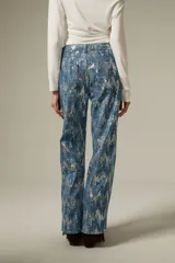 Pantalon de jean recto con acabado brillante de lentejuelas plateadas sobre base azul, de tiro medio.