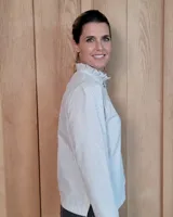 Camisa de manga larga con estampado de rayas verticales en tonos crudo y beige. Presenta cuello alto con volados, cierre frontal con botones dobles y puños con volados.