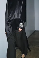 Blusa de Zara Woman Collection confeccionada en viscosa, con cuello alto, manga larga y diseño asimétrico en el bajo. Presenta un acabado satinado y cierre en la espalda.