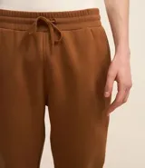 Pantalón de jogging masculino, color gris melange, confeccionado en algodón y poliéster. Presenta cintura elástica con cordón de ajuste y puños ajustados en los tobillos.