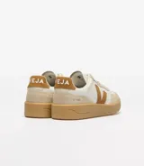Championes Veja modelo V-90, de diseño urbano con combinación de tonos crema, blanco y marrón. Presentan el logo lateral en forma de V, refuerzos de gamuza en la puntera y el talón, y una suela de goma color caramelo.