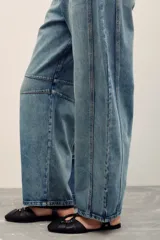 Jeans de corte barrel color celeste, confeccionados en 100% algodón, con diseño de perneras curvas y costuras decorativas en las rodillas.