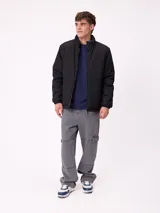 Campera reversible de nylon con cuello alto y cierre frontal. Un lado es de color gris liso con logo bordado, mientras que el otro lado presenta un estampado abstracto en tonos azules. Cuenta con bolsillos laterales y puños elásticos.