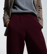 Pantalón de corte barrel en color bordó, confeccionado en tejido de algodón con felpa. Presenta cintura elástica, bolsillos laterales y pinzas en la zona de la rodilla que aportan volumen a la prenda.