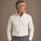 Camisa de manga larga confeccionada en algodón oxford, con cuello americano button-down y cierre frontal de botones. Presenta un diseño minimalista con un pequeño bordado en el pecho.