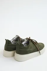 Zapatillas de gamuza verde oliva con cordones marrones y suela de goma color crema.