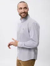 Camisa de manga larga con estampado de microcuadros en tonos azul y blanco. Presenta cuello clásico con botones, cierre frontal abotonado y detalle de logo bordado en el pecho.