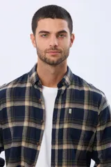 Camisa de viyela de manga larga con diseño de cuadros en tonos azul, verde y beige. Presenta cuello clásico con botones, cierre frontal abotonado y un bolsillo en el pecho con etiqueta de marca.