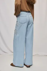 Jean wide leg blanco de tiro medio, con calce amplio y detalle de flores bordadas en los laterales.