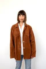 Blazer de gamuza color óxido, con solapas clásicas, cierre frontal de dos botones irregulares y bolsillos delanteros con solapa.