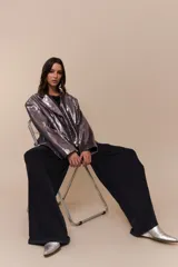 Blazer de corte sastre confeccionado en tejido cubierto de lentejuelas plateadas, con solapas clásicas y cierre frontal.