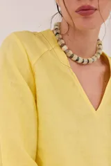 Blusa de lino color lila, de corte relajado y mangas largas amplias, con escote en V y ruedo curvo.