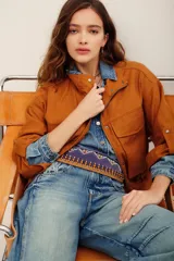 Campera tostado de estilo utilitario, con cuello alto, cierre frontal y bolsillos frontales con solapa. Presenta mangas largas con presillas.
