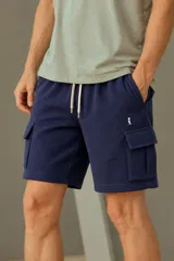 Bermuda cargo de color azul marino, confeccionada en tejido de punto texturizado. Cuenta con cintura elástica con cordón de ajuste en color crudo, bolsillos laterales y bolsillos cargo con solapa en las piernas. Presenta un pequeño logo bordado en blanco.
