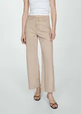 Pantalón jeans estilo culotte de tiro alto, color beige, con trabillas, cierre de cremallera y botón, bolsillos delanteros y traseros, y bajo deshilachado.