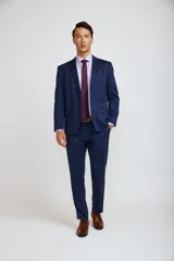 Ambo de corte slim compuesto por saco de dos botones y pantalón de vestir a juego, en color azul marino. El saco presenta solapas clásicas, bolsillos laterales con solapa y bolsillo en el pecho con pañuelo decorativo.