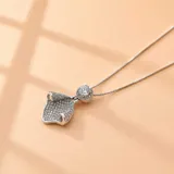 Collar de plata 925 con cadena fina y dije con forma de hoja o pétalo curvado, totalmente cubierto de pequeñas circonias brillantes, con una circonia central de mayor tamaño rodeada por un halo de piedras más pequeñas.