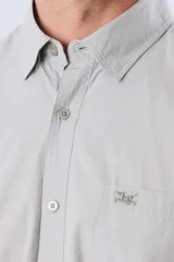Camisa de manga corta de algodón en color celeste con microdiseño geométrico a cuadros, cuello camisero y bolsillo frontal con logo bordado.