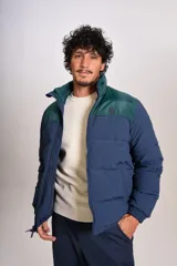 Campera puffer con diseño bicolor, cuerpo en azul marino y canesú superior en verde oscuro. Presenta cuello alto, cierre frontal completo y puños elásticos.