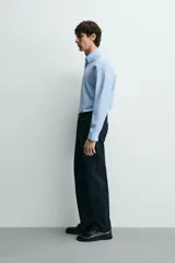 Camisa de corte slim fit, color negro, con cuello italiano, manga larga con puños abotonados y cierre frontal de botones. Confeccionada en tejido de fácil cuidado que minimiza la necesidad de planchado.