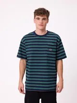 Remera de corte holgado con diseño de rayas horizontales en tonos azul marino, verde y blanco. Presenta cuello redondo, mangas cortas y un bolsillo frontal en el pecho con el logo de la marca.