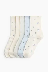 Pack de cinco pares de medias de corte clásico, confeccionadas en mezcla de algodón suave. El conjunto incluye diseños en tonos neutros y pasteles, con detalles de estampado floral disperso y un par en color gris liso. Presentan un borde superior enrollado.