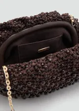 Bolso tipo clutch de tamaño pequeño, color marrón, elaborado en tejido de fibra natural con abalorios de madera incrustados y cierre a presión.