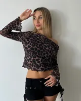 Blusa de tul con estampado animal print, de corte ajustado, manga larga y escote asimétrico con terminaciones onduladas.