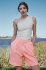 Bermuda de tiro alto color salmón con textura broderie, corte amplio, pinzas delanteras y ruedo con dobladillo.