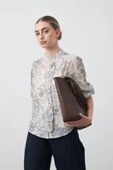 Camisa de manga larga con cuello con volados y botones nacarados. Presenta un estampado romántico de inspiración barroca en tonos azul y beige.
