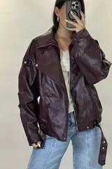 Chaqueta de ecocuero negro con diseño oversize, cuello solapa, cierre frontal y cinturón ajustable en el ruedo.