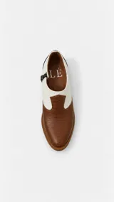 Zapatos de cuero bicolor, combinando blanco en la parte superior y marrón con textura símil reptil en la puntera, con cierre lateral mediante hebilla.