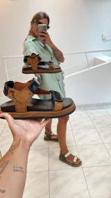 Sandalias planas tipo cangrejeras color verde militar y beige, con suela marrón y tiras ajustables con velcro.