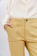 Pantalon de corte recto confeccionado en cuero ovino con acabado metalizado en color plata. Presenta cierre frontal con cremallera y bolsillos laterales.