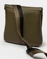 Bandolera color beige con correa ancha de tela negra con el nombre de la marca en blanco.