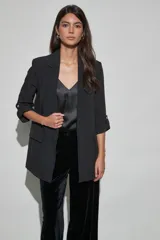Blazer negro de corte recto con solapa clásica y mangas tres cuartos con detalles de trabilla y botón metálico.