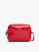 Cartera tipo bandolera de Tommy Jeans con acabado brillante y liso. Presenta un diseño rectangular con cierre de cremallera superior, correa ajustable y una insignia con el logo de la marca grabado en el centro de la parte frontal.