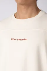 Remerón de corte oversized confeccionado en tejido rústico, con cuello redondo y mangas cortas. Presenta un diseño minimalista con una pequeña estampa frontal centrada en el pecho.