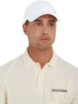 Gorra de béisbol Tommy Hilfiger de seis paneles, color blanco, con logo metálico en el frente y hebilla de ajuste metálica en la parte trasera.