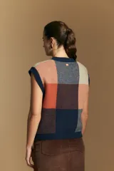 Chaleco tejido de punto con diseño de bloques a cuadros en tonos rosados, marrones y beige. Presenta cuello redondo y terminaciones acanaladas en cuello y sisas.