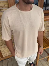 Remera de punto con textura tipo waffle, color beige, de corte holgado y manga corta con cuello redondo.